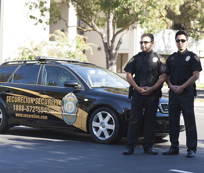 two Securelion Security guards standing next to a security car in california